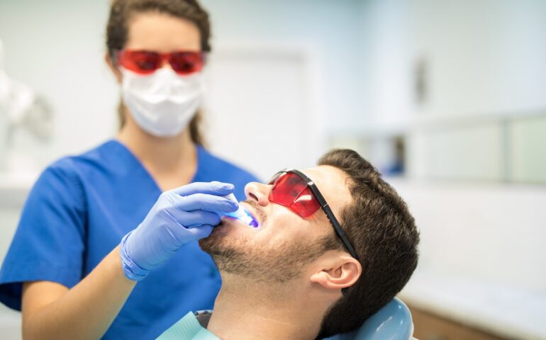 Dentist Checking Man With Ultraviolet Light In Clinic